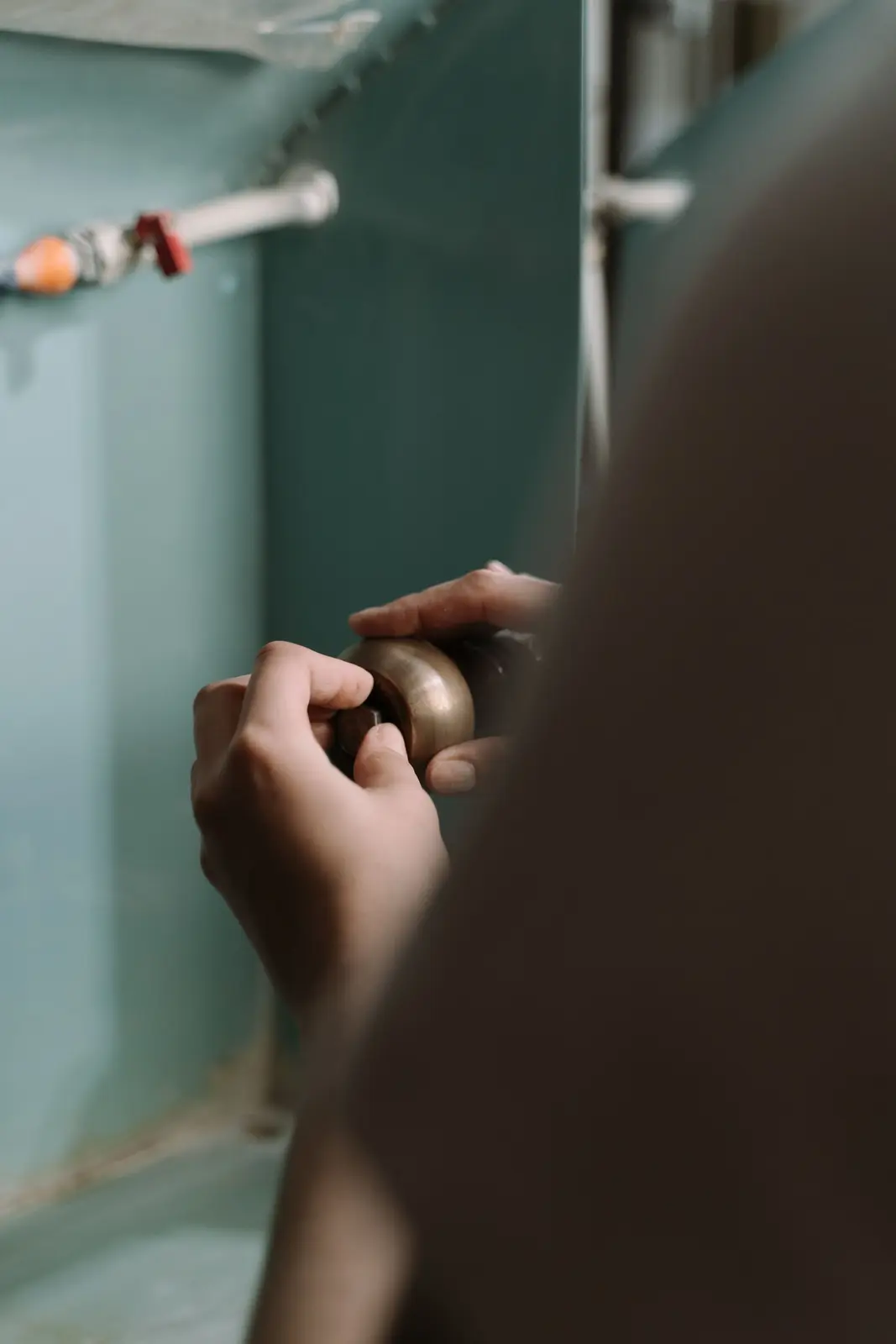 Manos ajustando una tubería bajo el fregadero